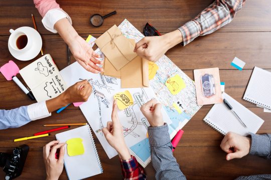 Picture of businessmen's hands on wooden table with documents, coffee and drafts